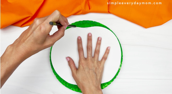 hand using template to cut out paper plate
