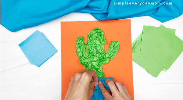 hands using tissue paper to place onto printed template of cactus
