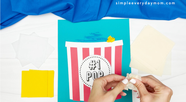 hands scrunching tissue paper square to glue to popcorn craft