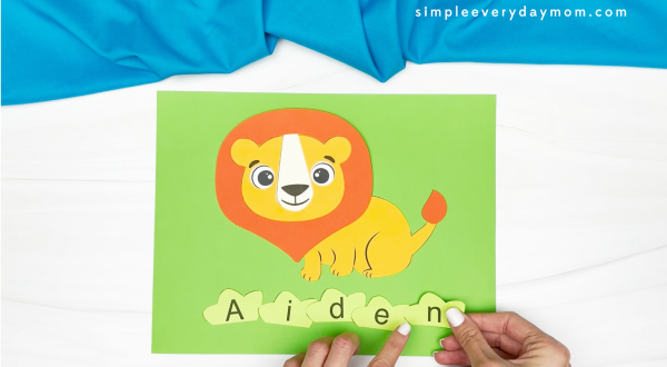 hands finished gluing all letters of name to lion craft