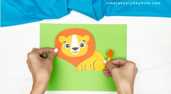 hands gluing finished lion to sheet of paper