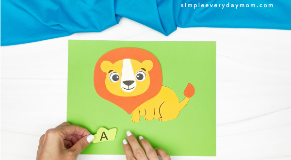 hands gluing letters of name to lion craft