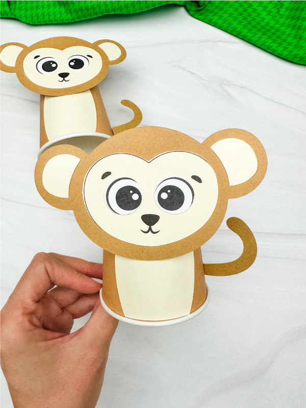 hand holding finished monkey paper cup craft with another in background