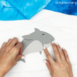 hands gluing pieces of shark body together
