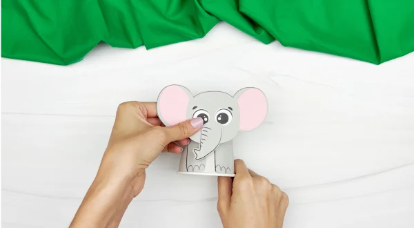 hands gluing elephant face to cup body