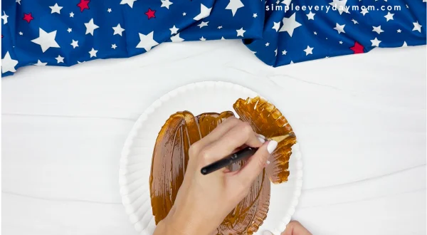 hand painting paper plate with brown paint