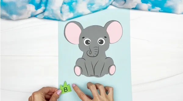 hands gluing letters onto elephant name craft