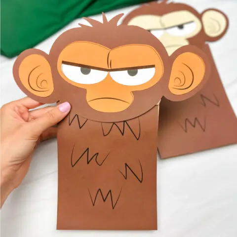 hand holding grumpy monkey craft with another example in the background