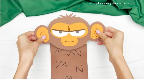 hands gluing monkey face onto bag