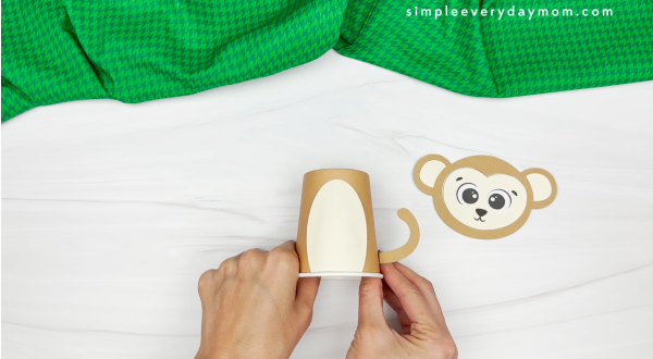 hands gluing monkey tail to paper cup