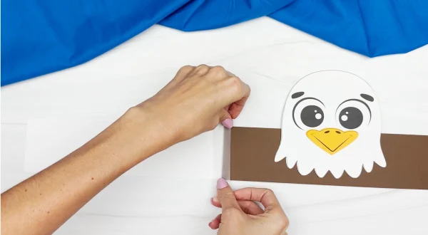 hands gluing brown paper to represent feathers onto eagle body