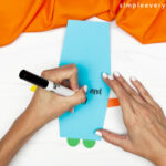 hands using a black marker to write a note inside robot card