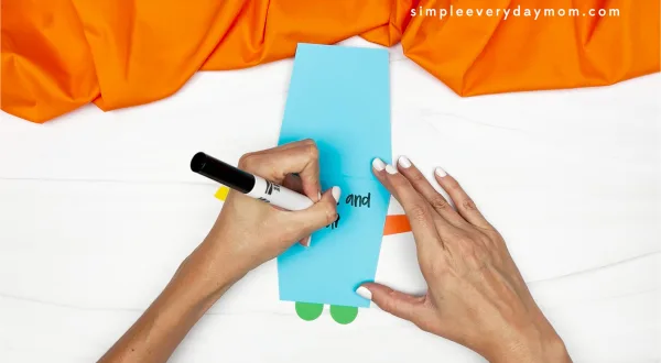 hands using a black marker to write a note inside robot card