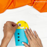 hands gluing eyes onto robot head