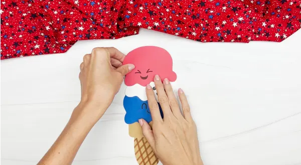 hands gluing red ice cream on top of white ice cream