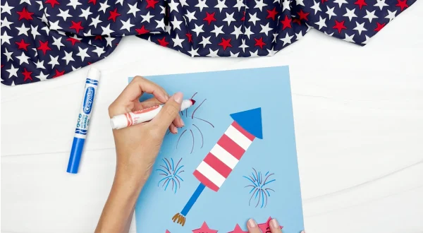 hands using markers to draw fireworks onto background paper