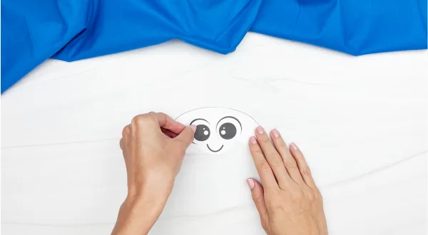 hands gluing eyes onto marshmallow