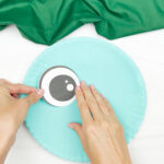 hand gluing the eyes of dinosaur paper plate craft