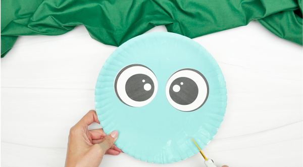spreading glue at the bottom of the eyes of dinosaur paper plate craft