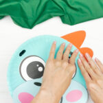 hand gluing the head to the body of dinosaur paper plate craft