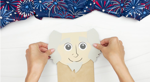 hands gluing Uncle Sam head to brown paper bag flap