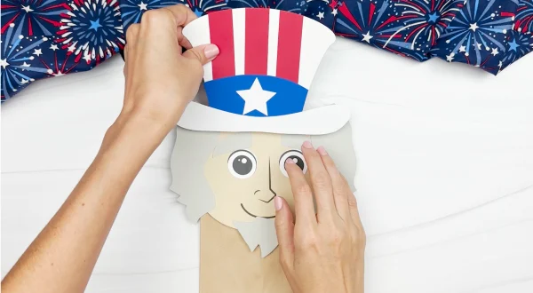 hands gluing hat to Uncle Sam puppet craft