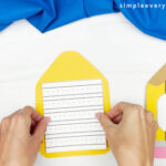 hands gluing printed lined paper to pencil book