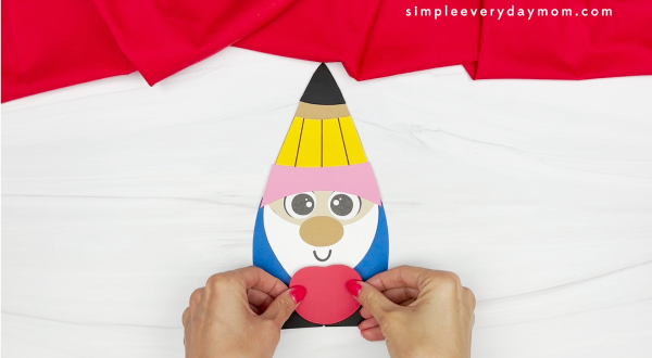 hands gluing apple to back to school gnome craft