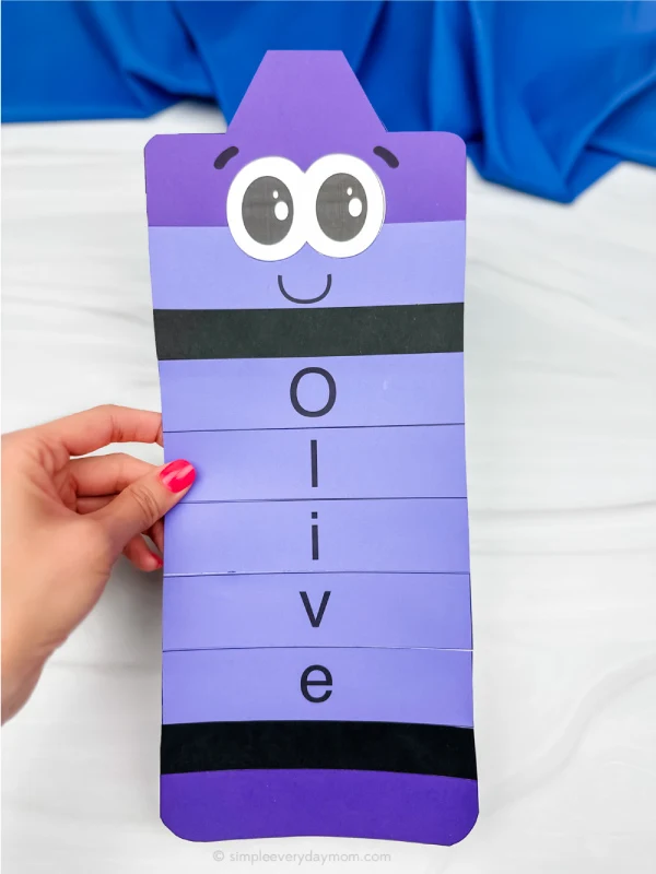 hand holding finished crayon name craft in purple