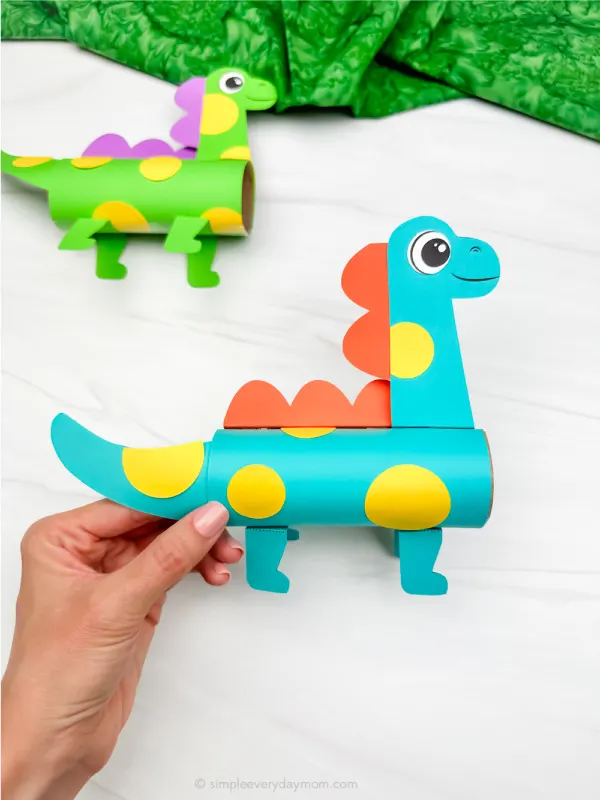 hand holding finished dinosaur tp roll craft with another example in background