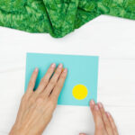 hands gluing yellow spots to paper