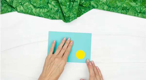 hands gluing yellow spots to paper