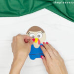 hands gluing beak onto basketball turkey craft