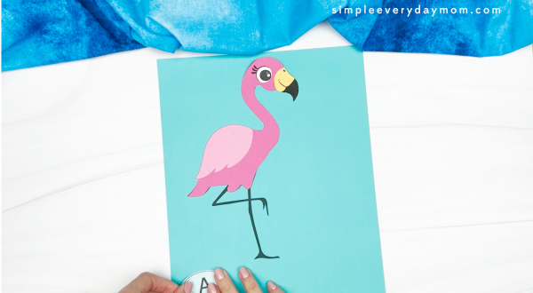 hands gluing letter a to flamingo backdrop