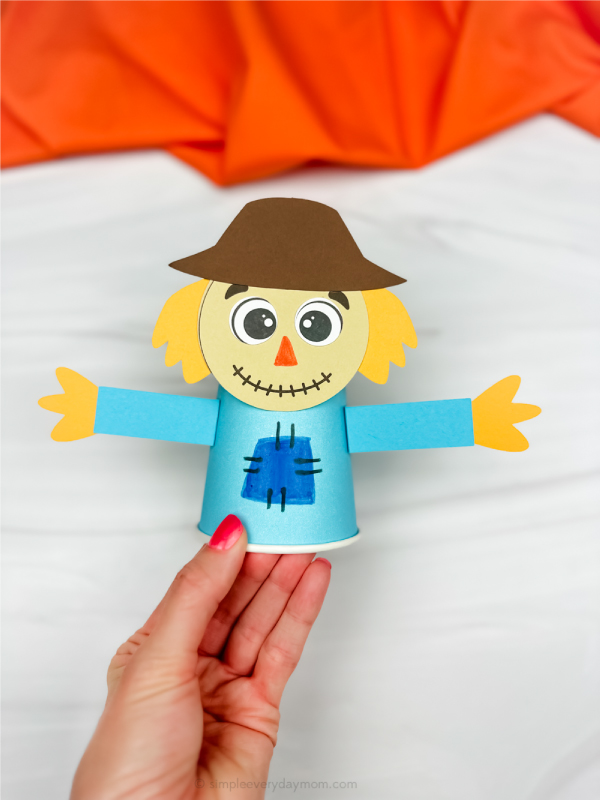 hand holding finished scarecrow paper cup craft
