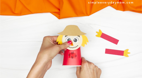 hands gluing scarecrow head to paper cup