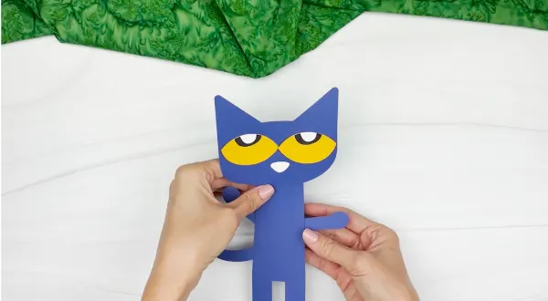 hands gluing head to body of Pete the cat