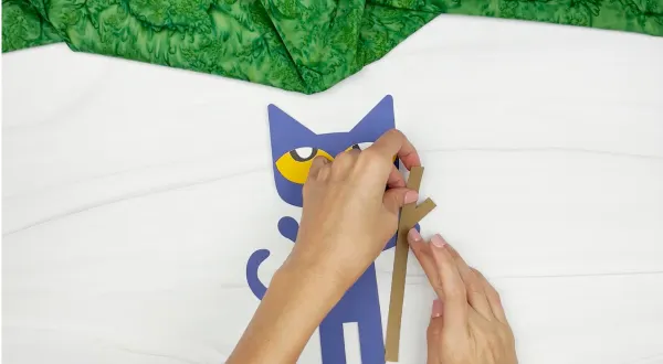 hands gluing hiking stick to Pete the cat