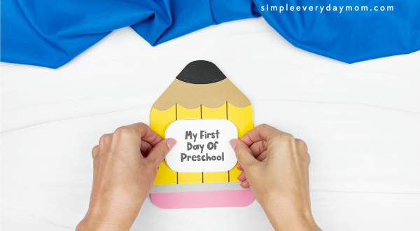 hands gluing "my first day of preschool" sign to pencil