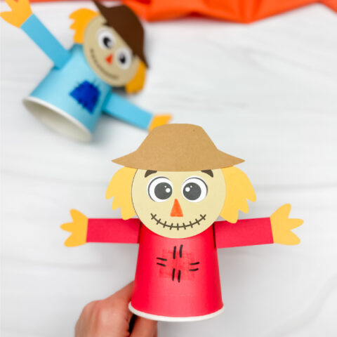 hand holding scarecrow paper cup craft with another in the background