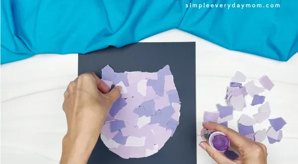 hands gluing more purple paper to template