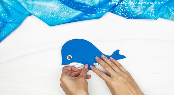 hands gluing fin to whale