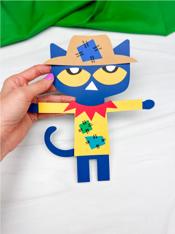 hand holding Pete the cat scarecrow craft