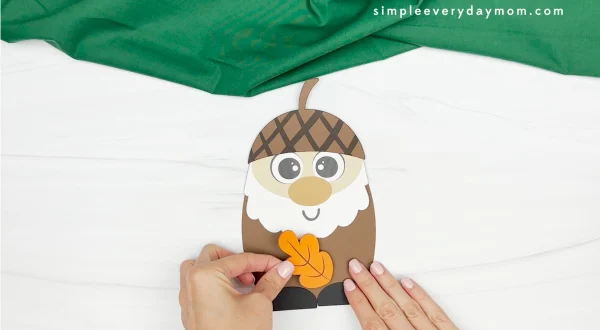 hands gluing leaf to gnome body