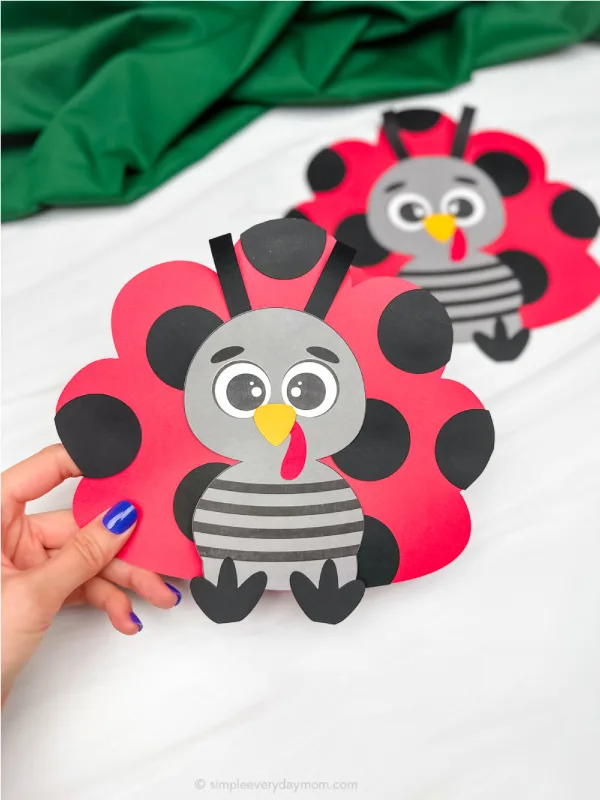 hand holding ladybug turkey disguise craft with another example in the background