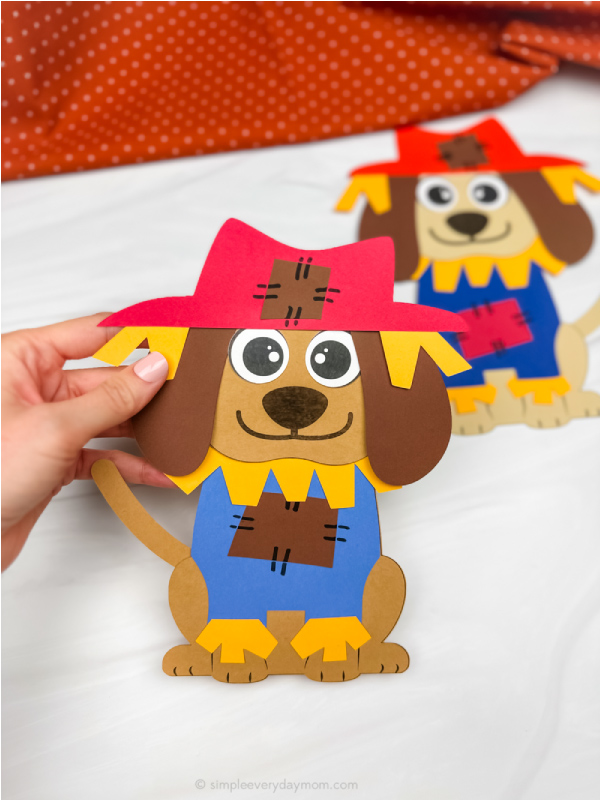 hand holding scarecrow dog craft with another in background