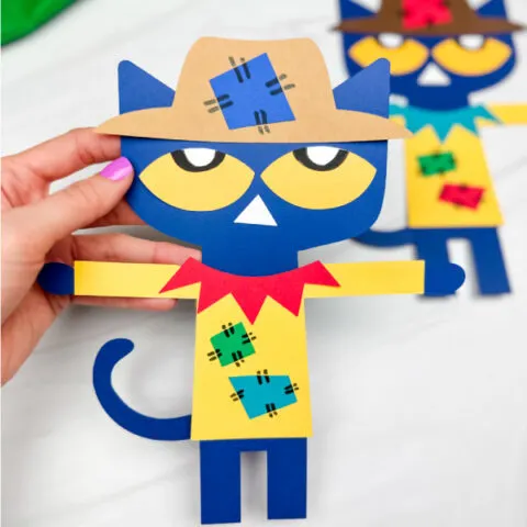 hand holding Pete the cat scarecrow craft with another example in background