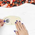 hands gluing eye to pumpkin face