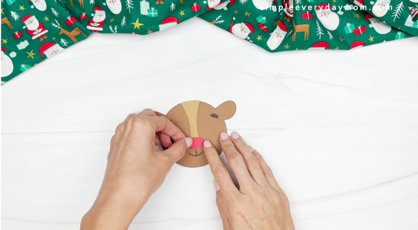 hands gluing red nose to reindeer
