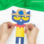 hands gluing collar to shirt on Pete the cat scarecrow craft
